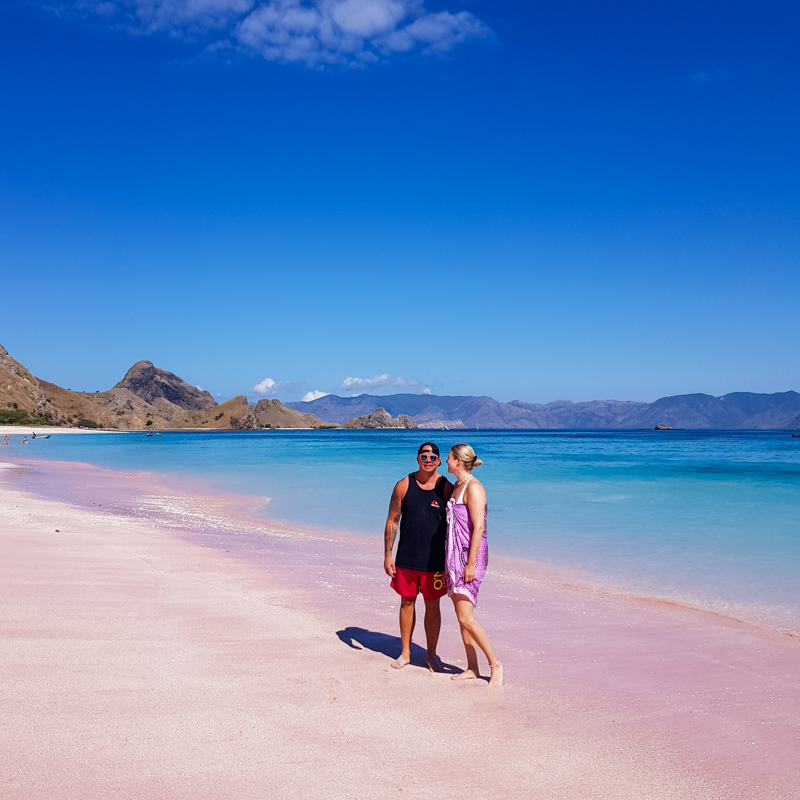 man and woman standing in a pink beach